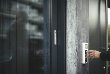 Ausgeschnittenes Bild der Hand eines Geschäftsmannes, der den Sicherheitscode eingibt, um die Bürotür zu öffnen - MASF02519