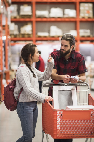 Ehepaar diskutiert mit Einkaufswagen in einem Baumarkt, lizenzfreies Stockfoto