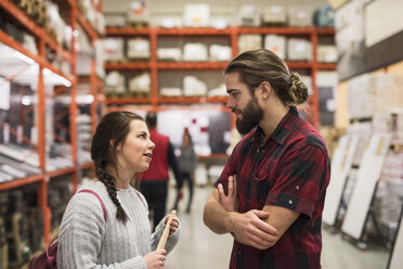 Couple discussing while standing in hardware store - MASF02527