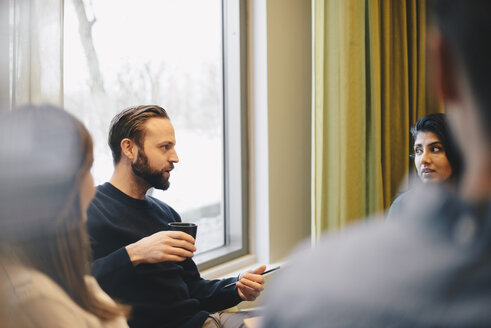 Confident businessman discussing with colleagues in board room meeting - MASF02539