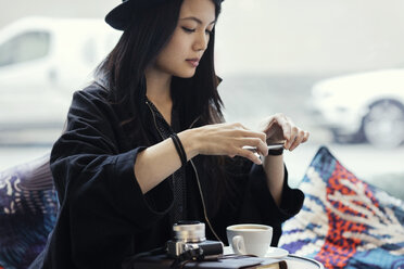 Junge Frau fotografiert Kaffee mit ihrem Smartphone im Kreativbüro - MASF02556