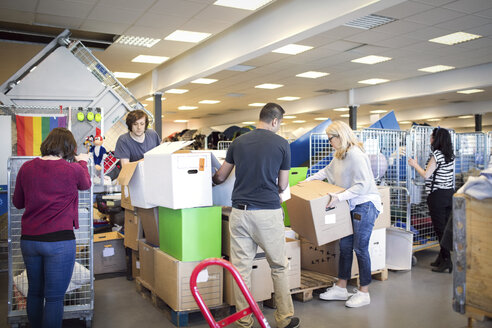 Volunteers arranging cardboard boxes while working in workshop - MASF02573