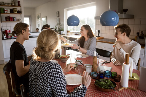 Woman serving food for family at dining table - MASF02580