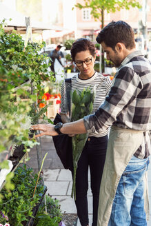 Frau kauft Blumen von männlichem Besitzer auf dem Bürgersteig - MASF02590