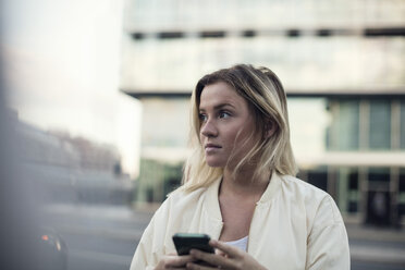 Junge Frau mit Mobiltelefon vor einem Gebäude in der Stadt - MASF02621