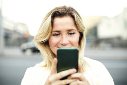 Junge Frau benutzt ein Mobiltelefon in der Stadt - MASF02622