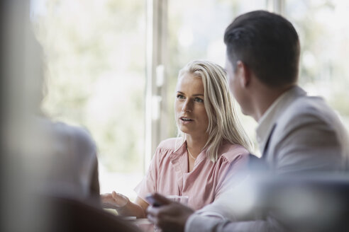 Blond businesswoman talking with colleagues during meeting at restaurant - MASF02663