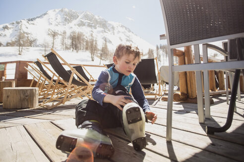 Junge mit Skistiefeln am Sitz auf dem Bodenbrett - MASF02668