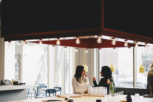 Businesswomen discussing at table in brightly lit office - MASF02707