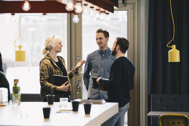 Businesswoman discussing with male colleagues in brightly lit office - MASF02708