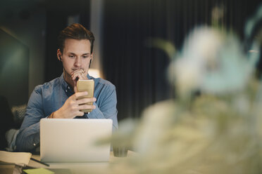 Businessman using smart phone at desk in office - MASF02712