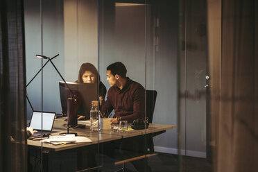 Business people discussing while working at desk in dark office - MASF02719