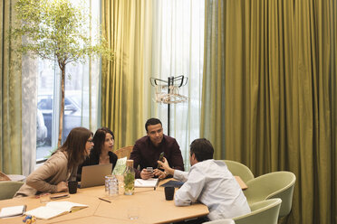 Businessman showing mobile phone to colleagues during meeting at office - MASF02722