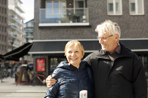 Lächelndes älteres Paar, das vor einem Gebäude steht - MASF02741