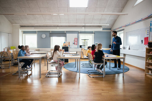 Lehrer unterrichtet Schüler in einem hell erleuchteten Klassenzimmer in der Schule - MASF02756