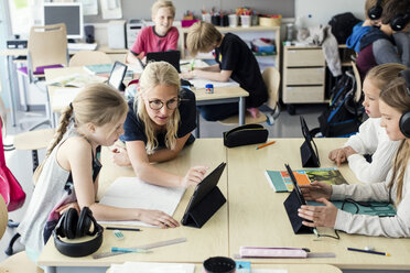 Lehrerin unterstützt Schülerin bei der Nutzung eines digitalen Tablets im Klassenzimmer - MASF02769