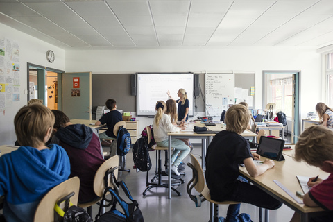 Lehrer erklärt Studenten durch Whiteboard im Klassenzimmer, lizenzfreies Stockfoto