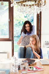 Smiling teenage girls reading book at table - MASF02785