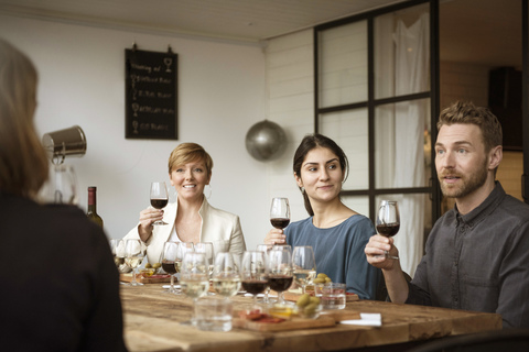 Lächelnde Geschäftsleute, die ein Weinglas in der Hand halten und am Tisch sitzen, lizenzfreies Stockfoto
