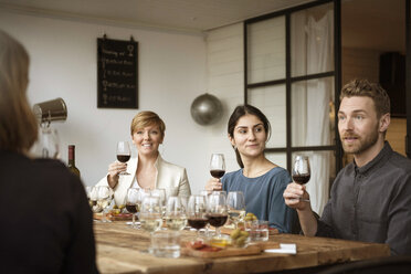 Lächelnde Geschäftsleute, die ein Weinglas in der Hand halten und am Tisch sitzen - MASF02807