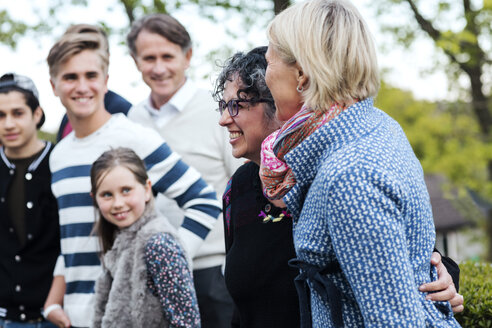 Lächelnde reife Frau mit Familie und Freunden im Garten - MASF02819