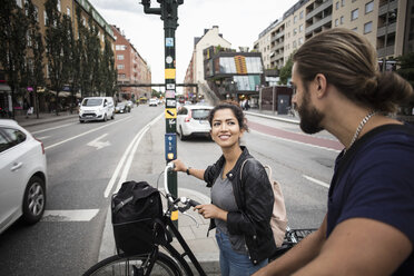 Lächelnde Frau mit Fahrrad, die ihren Freund anschaut, während sie mitten in der Stadt steht - MASF02824