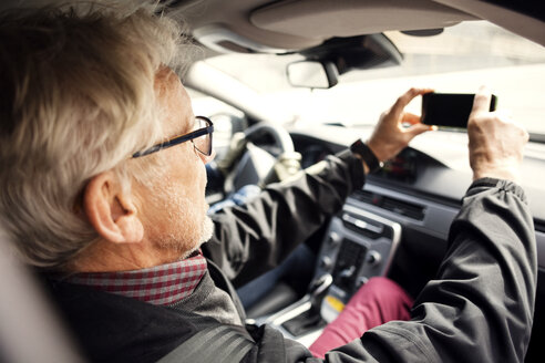 Älterer Mann fotografiert mit Smartphone durch die Windschutzscheibe eines Autos - MASF02838