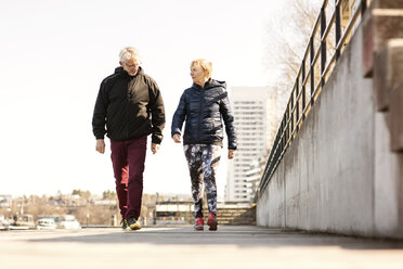 Senior couple in sportswear walking on sidewalk against clear sky - MASF02844