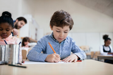 Serious boy studying while sitting in classroom at school - MASF02855