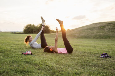 Seitenansicht einer Frau mit Blick auf ihre Tochter, die bei Sonnenuntergang im Park auf dem Rasen trainiert - MASF02876