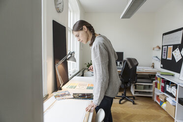 Serious woman looking at canvas while standing in creative office - MASF02882