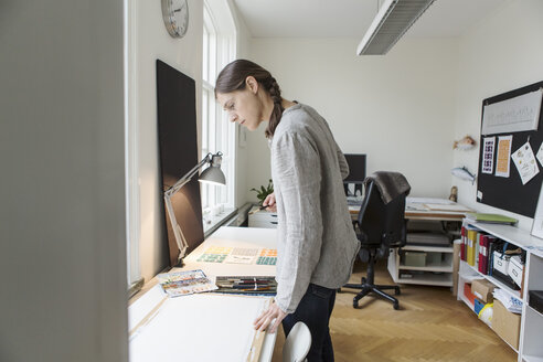 Ernste Frau, die auf eine Leinwand schaut, während sie in einem kreativen Büro steht - MASF02882