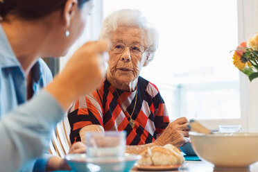 Senior woman talking to daughter while having food at home - MASF02891