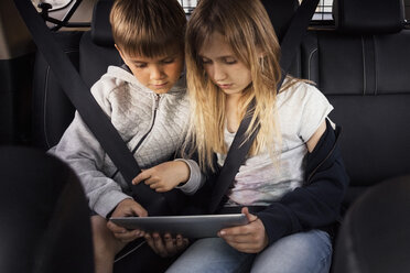 Geschwisterkind benutzt digitales Tablet, während es im Elektroauto sitzt - MASF02902