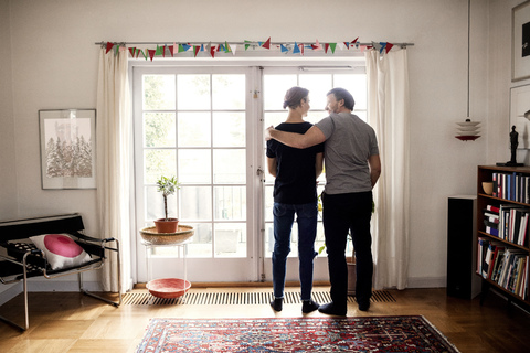 Rückansicht von Vater und Sohn vor der Tür des neuen Hauses, lizenzfreies Stockfoto