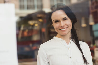 Porträt eines lächelnden Kunden durch ein Glasfenster gesehen - MASF02936