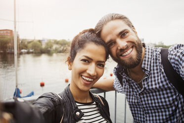 Portrait of smiling couple standing by river in city against clear sky - MASF02942