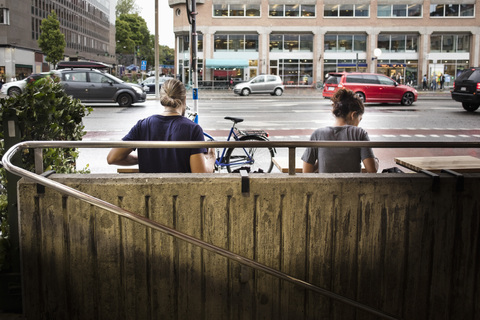 Rear view of man and woman sitting at sidewalk cafe in city stock photo