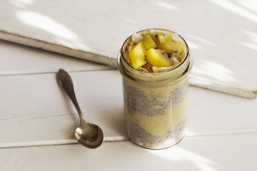 Glas Chia-Pudding mit Mango-Smoothie, garniert mit Kiwi und Kokosflocken - EVGF03357