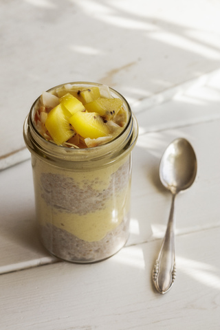 Glas Chia-Pudding mit Mango-Smoothie, garniert mit Kiwi und Kokosflocken, lizenzfreies Stockfoto