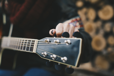 Junge Frau stimmt Gitarre, Nahaufnahme, lizenzfreies Stockfoto