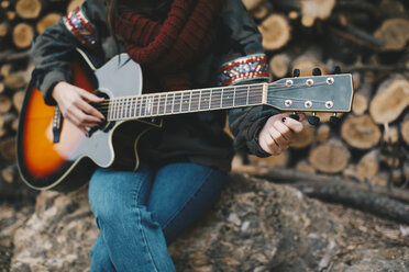 Junge Frau stimmt Gitarre im Freien, Teilansicht - OCAF00183