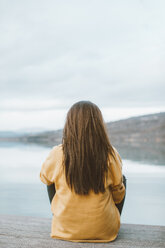 Back view of young woman sitting on jetty - OCAF00205