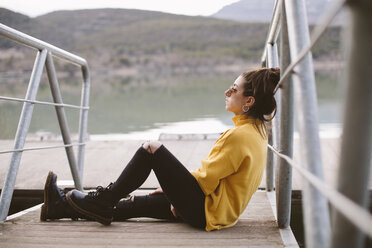 Pensive young woman relaxing on jetty - OCAF00208