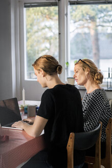 Mother and son using laptop at dining table by window - MASF02976