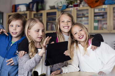 Porträt von Freunden mit einem Mädchen, das ein Tablet im Klassenzimmer benutzt - MASF02989