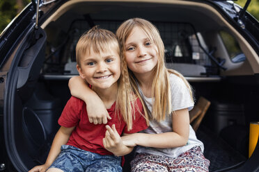 Porträt eines glücklichen Mädchens und eines Jungen, die im Kofferraum eines Autos sitzen - MASF03003