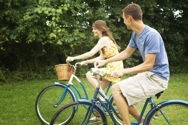 Happy couple riding bicycle in park - CAVF36255