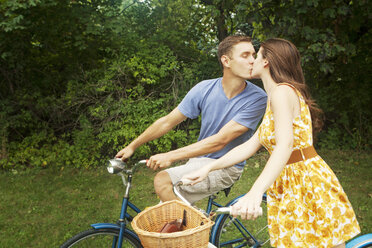 Pärchen küsst sich beim Fahrradfahren im Park - CAVF36257