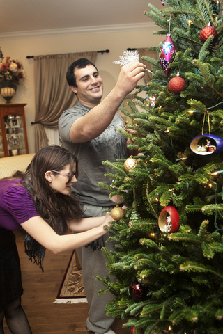 Ehepaar schmückt Weihnachtsbaum zu Hause, lizenzfreies Stockfoto